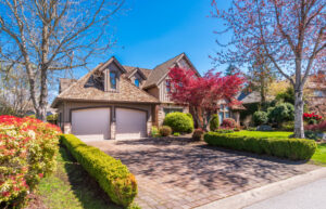 Una lujosa casa de estilo Tudor con entrada de ladrillo, garaje para dos coches y un vibrante arce japonés de color rojo en un soleado barrio de Chicago.