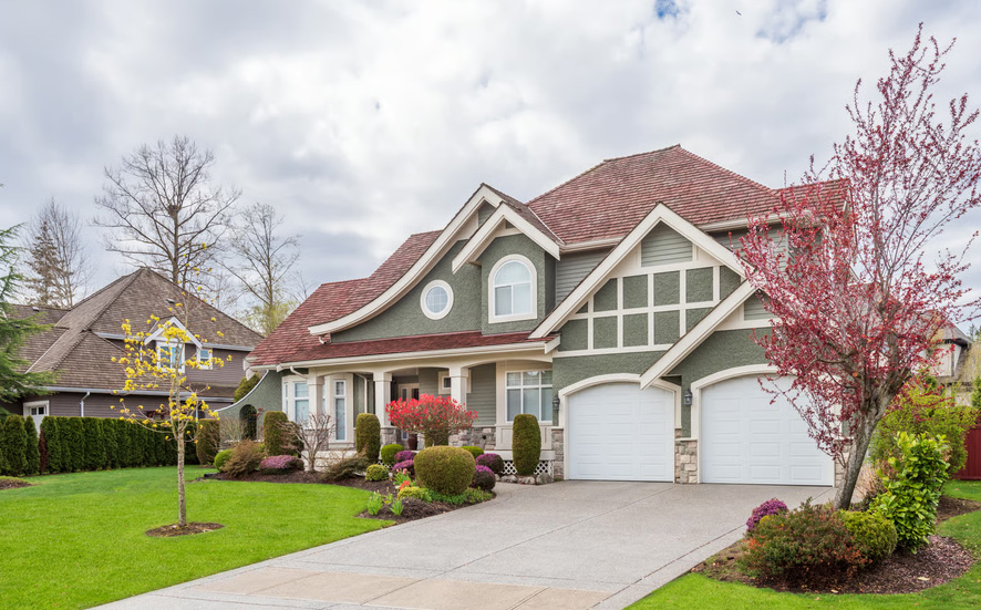 Beautiful green two-story home with a wide driveway and landscaped front yard representing home equity potential.
