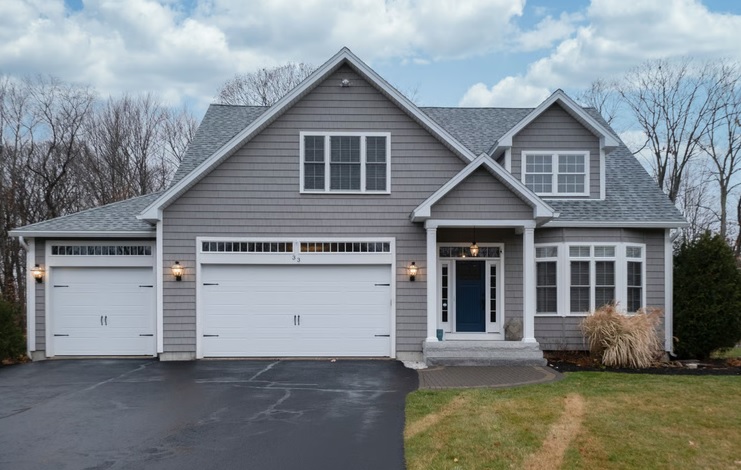 Gray two-story suburban single-family house with white double garage doors and paved driveway in Illinois