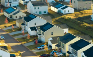 Aerial elevated view of a suburban residential neighborhood with single-family homes and solar panels.
