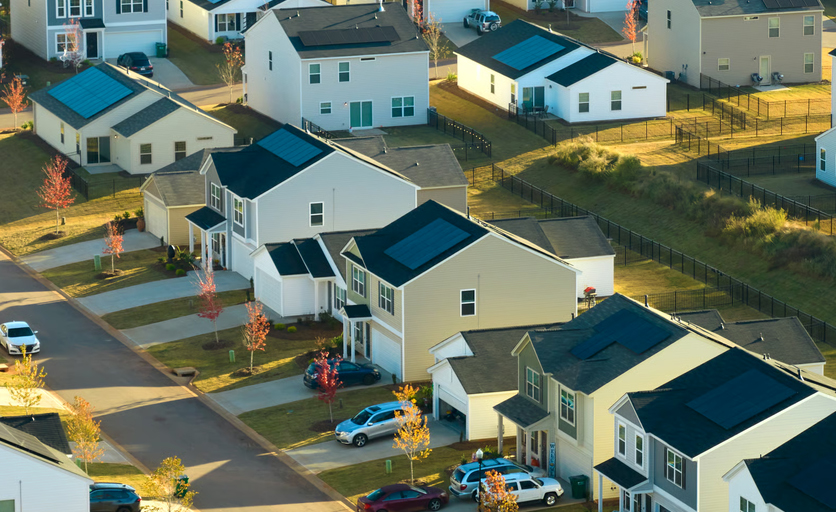 Aerial elevated view of a suburban residential neighborhood with single-family homes and solar panels.